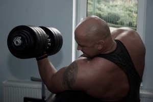 Kamil Bazelak podczas treningu bicepsów z 45kg sztangielką